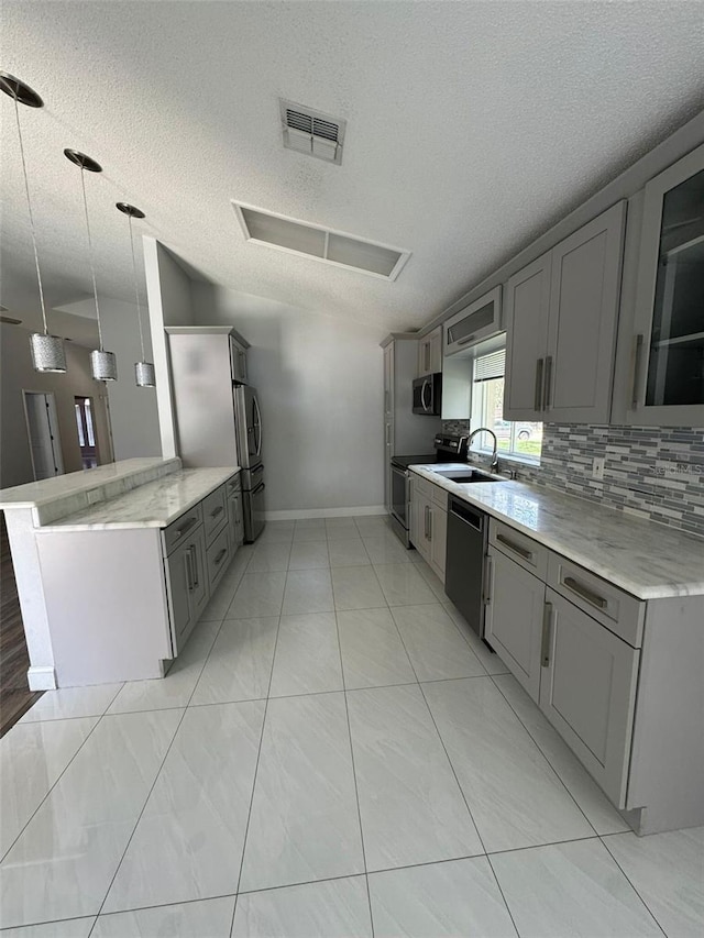 kitchen with sink, a textured ceiling, decorative light fixtures, kitchen peninsula, and stainless steel appliances