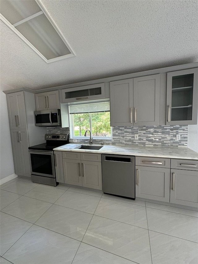 kitchen featuring gray cabinetry, sink, light tile patterned floors, and stainless steel appliances