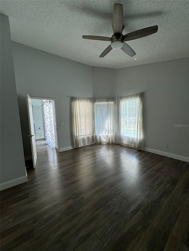 empty room with a textured ceiling, ceiling fan, and dark wood-type flooring