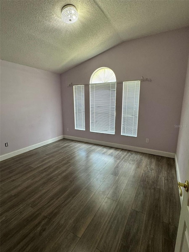 spare room with a textured ceiling, dark wood-type flooring, and vaulted ceiling