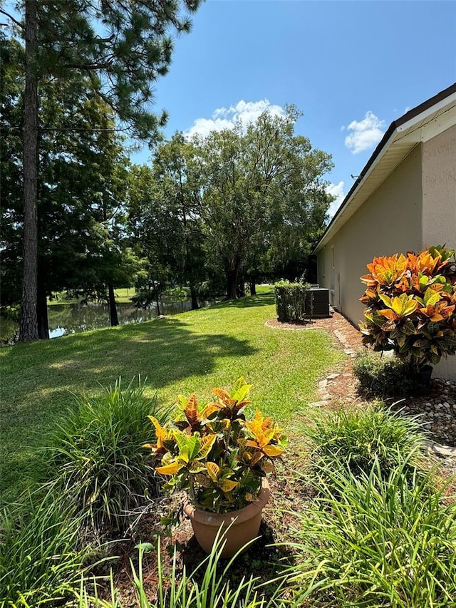 view of yard featuring a water view and central air condition unit