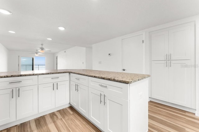 kitchen featuring light stone countertops, ceiling fan, light wood-type flooring, and white cabinetry