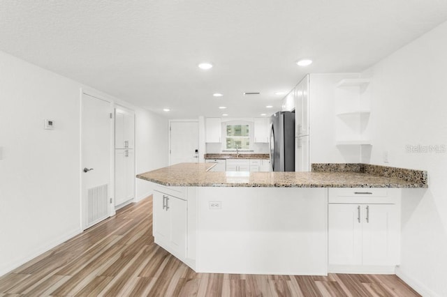 kitchen featuring light wood-type flooring, white cabinetry, and kitchen peninsula