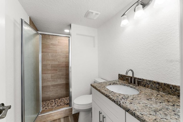 bathroom featuring an enclosed shower, vanity, a textured ceiling, hardwood / wood-style floors, and toilet