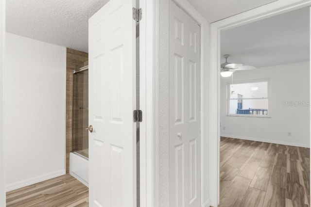 hallway featuring a textured ceiling and light hardwood / wood-style flooring