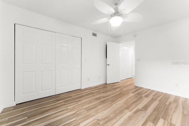 unfurnished bedroom featuring ceiling fan, a closet, and light wood-type flooring