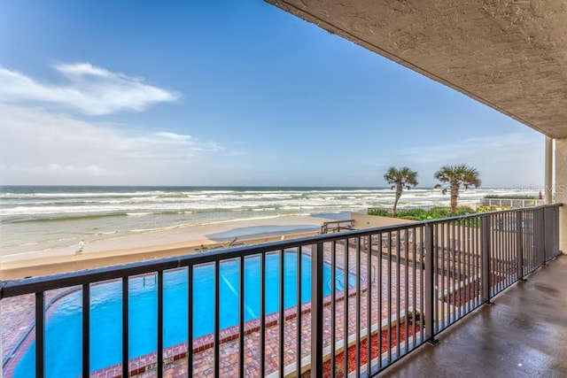 balcony with a water view and a view of the beach