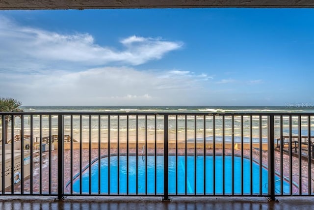 view of pool featuring a water view and a view of the beach