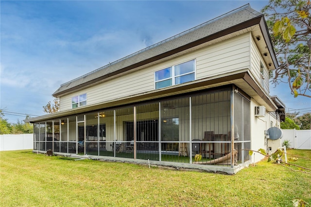 rear view of house with a wall unit AC, a sunroom, and a yard