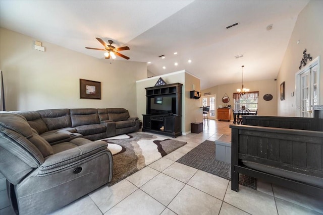 tiled living room with ceiling fan with notable chandelier and vaulted ceiling