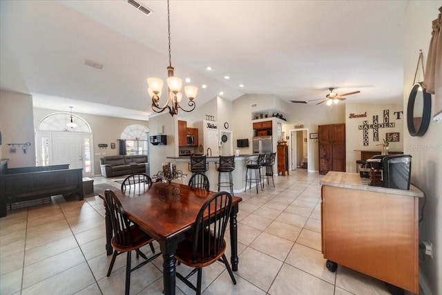 tiled dining space with ceiling fan with notable chandelier and lofted ceiling