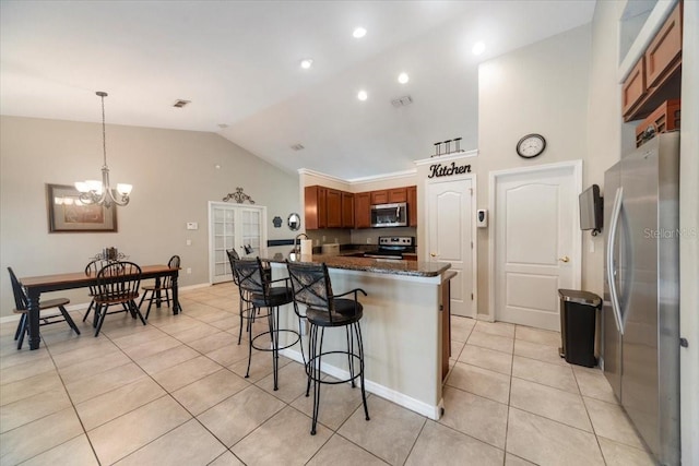 kitchen featuring pendant lighting, dark stone counters, vaulted ceiling, light tile patterned floors, and appliances with stainless steel finishes