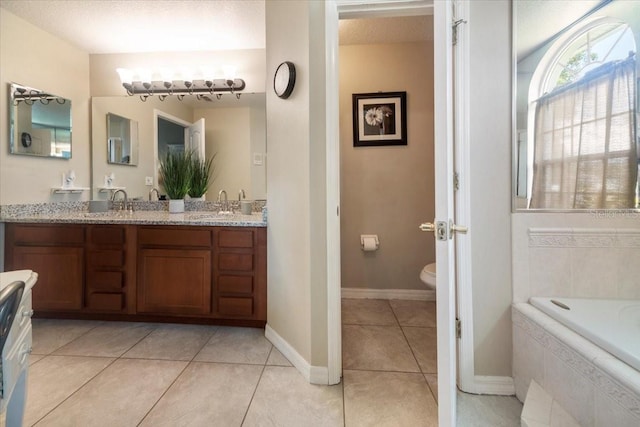 bathroom featuring a textured ceiling, vanity, tiled tub, tile patterned flooring, and toilet