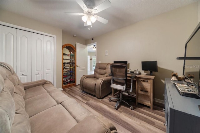 home office with ceiling fan, a textured ceiling, and light hardwood / wood-style flooring