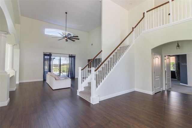 interior space featuring decorative columns, dark hardwood / wood-style floors, ceiling fan, and a high ceiling