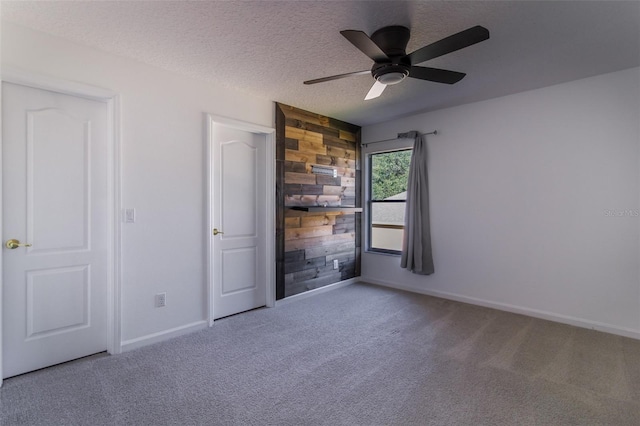 unfurnished bedroom with ceiling fan, carpet floors, a textured ceiling, and wood walls