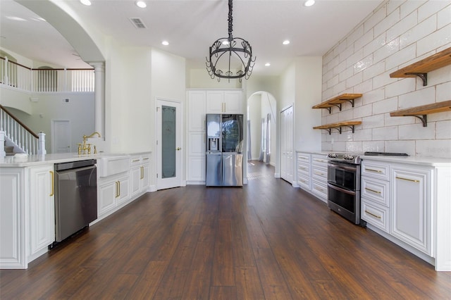 kitchen with appliances with stainless steel finishes, pendant lighting, sink, white cabinets, and dark wood-type flooring