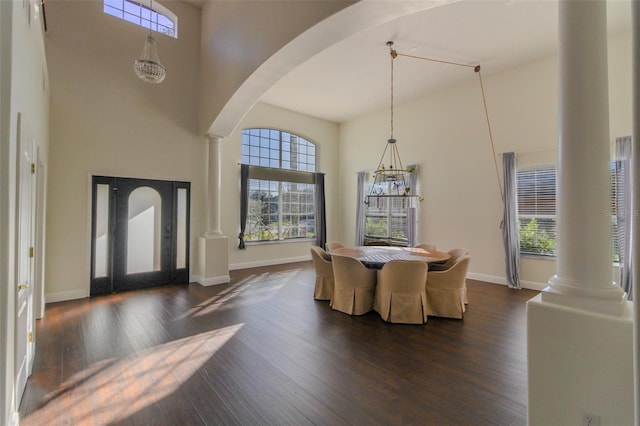 dining room with a towering ceiling, dark wood-type flooring, and ornate columns