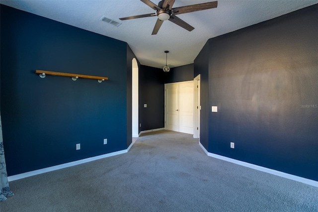 unfurnished bedroom with ceiling fan, light carpet, and a textured ceiling