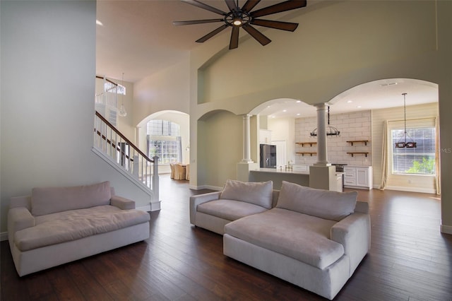 living room with decorative columns, a high ceiling, and dark hardwood / wood-style floors