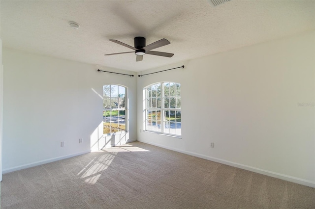 spare room with ceiling fan, light carpet, and a textured ceiling