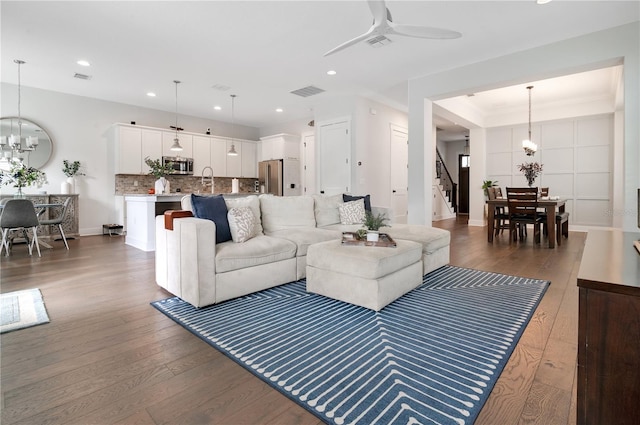 living room with ceiling fan with notable chandelier and dark wood-type flooring