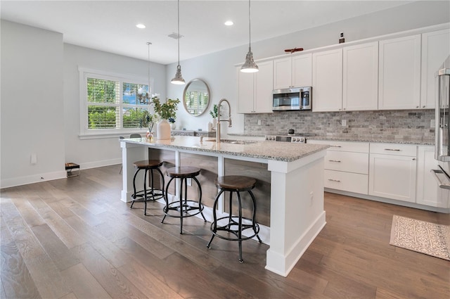 kitchen featuring white cabinets, appliances with stainless steel finishes, a kitchen island with sink, and sink