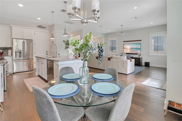 dining space with dark hardwood / wood-style flooring, an inviting chandelier, and sink