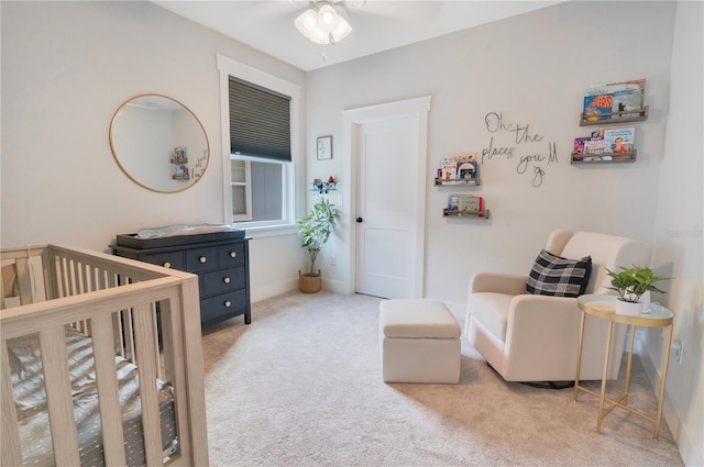 bedroom featuring ceiling fan, light carpet, and a nursery area