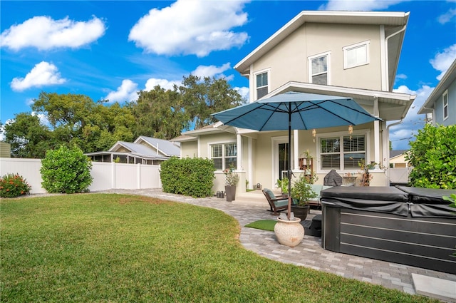 rear view of house with a patio, a yard, and a hot tub