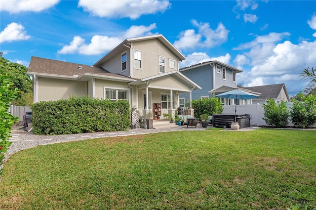 rear view of property with a lawn, a patio area, and a hot tub