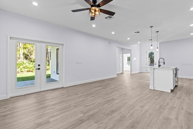 unfurnished living room featuring ceiling fan, french doors, sink, and light hardwood / wood-style flooring