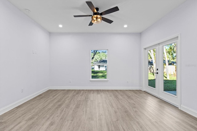 empty room with ceiling fan, light wood-type flooring, and french doors