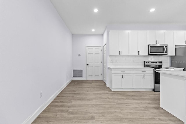 kitchen with white cabinets, light wood-type flooring, stainless steel appliances, and tasteful backsplash