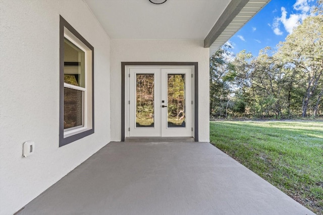 view of exterior entry featuring a yard, french doors, and a patio