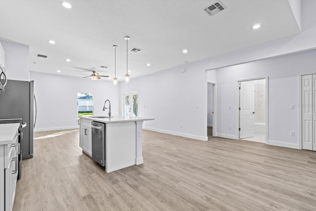 kitchen with a center island with sink, white cabinets, ceiling fan, light wood-type flooring, and stainless steel appliances