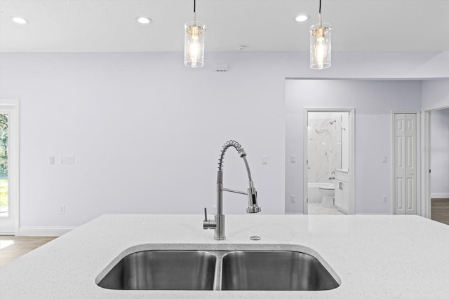 kitchen featuring pendant lighting, light stone countertops, sink, and hardwood / wood-style floors