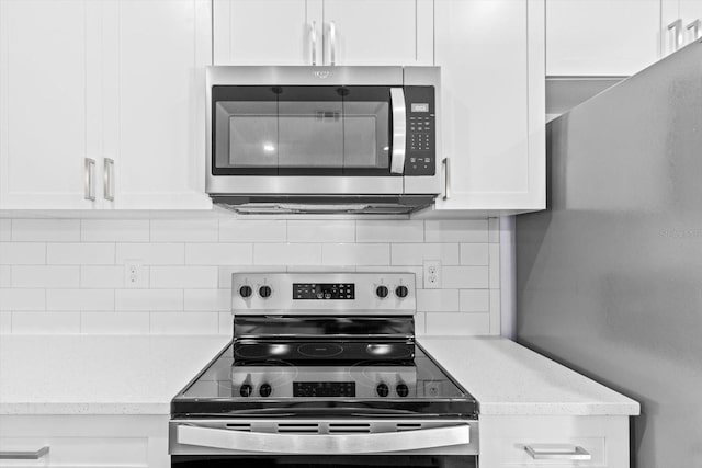 kitchen with backsplash, light stone counters, white cabinets, and stainless steel appliances