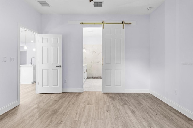 unfurnished room featuring light wood-type flooring and a barn door