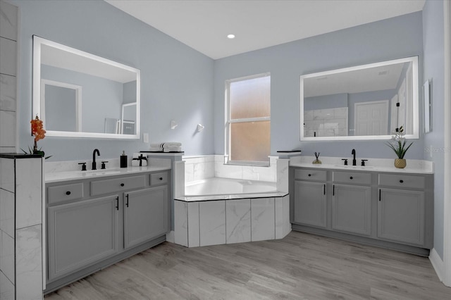 bathroom featuring tiled bath, vanity, and hardwood / wood-style flooring