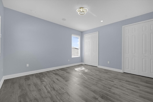 unfurnished bedroom featuring multiple closets and wood-type flooring