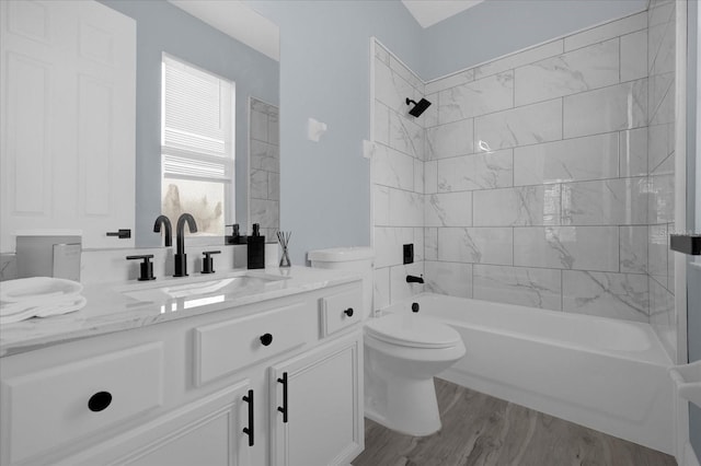 full bathroom featuring hardwood / wood-style flooring, vanity, toilet, and tiled shower / bath