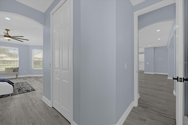 corridor with ornamental molding and light wood-type flooring