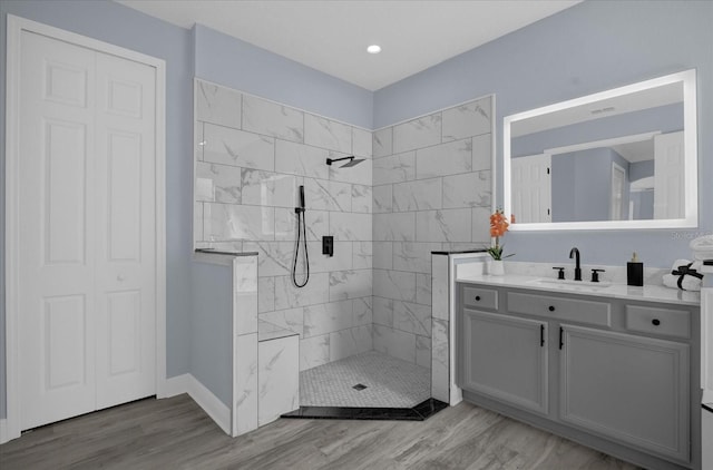 bathroom featuring a tile shower, hardwood / wood-style floors, and vanity