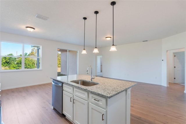 kitchen featuring light stone countertops, white cabinets, sink, dishwasher, and an island with sink