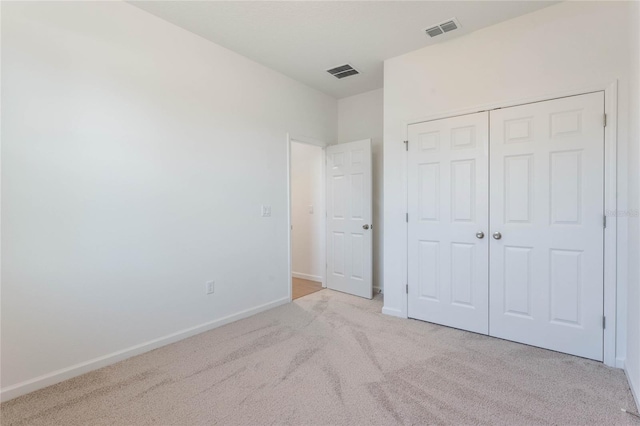 unfurnished bedroom with light carpet and a closet