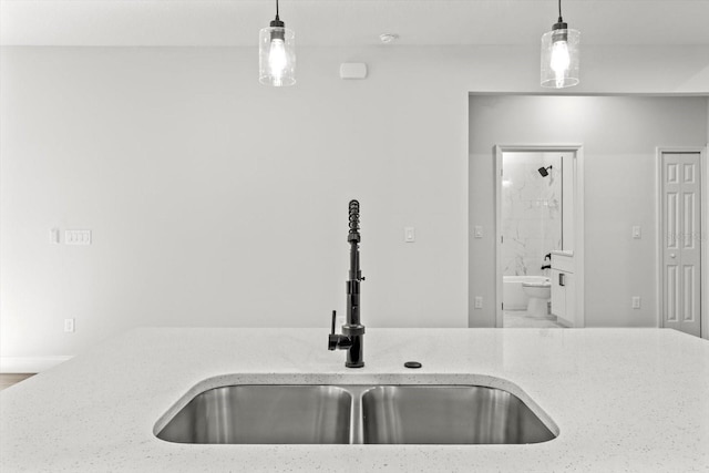 kitchen with decorative light fixtures, light stone countertops, and sink