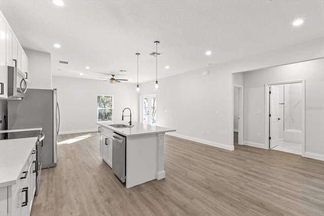 kitchen with white cabinets, sink, a kitchen island with sink, and hanging light fixtures