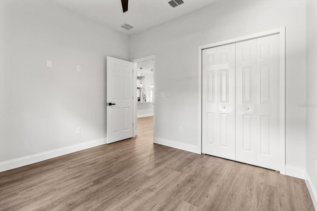 unfurnished bedroom featuring hardwood / wood-style flooring, ceiling fan, and a closet