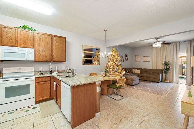 kitchen featuring kitchen peninsula, white appliances, ceiling fan with notable chandelier, sink, and pendant lighting